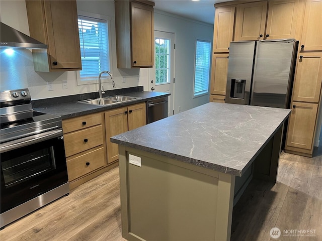 kitchen featuring wall chimney exhaust hood, sink, a kitchen island, stainless steel appliances, and light hardwood / wood-style floors