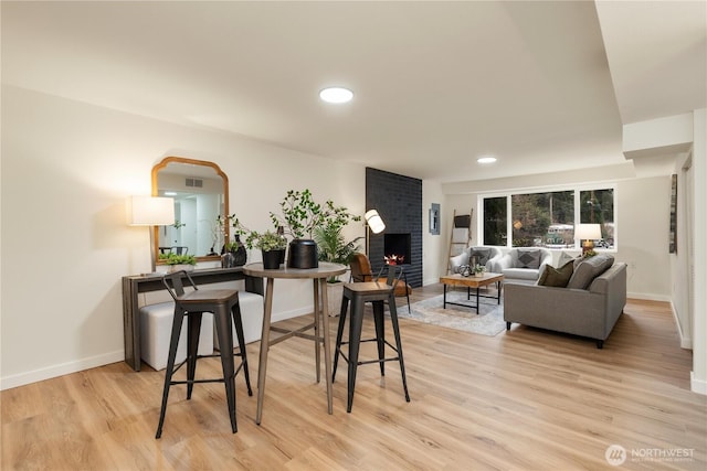 dining room with light wood-type flooring and a fireplace