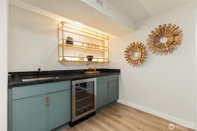 bar featuring wine cooler, sink, and light wood-type flooring