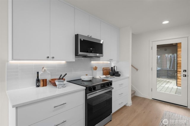 kitchen featuring range with electric cooktop, white cabinetry, decorative backsplash, and light wood-type flooring