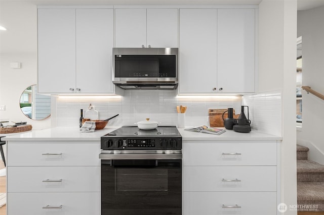 kitchen with white cabinets, backsplash, and electric stove