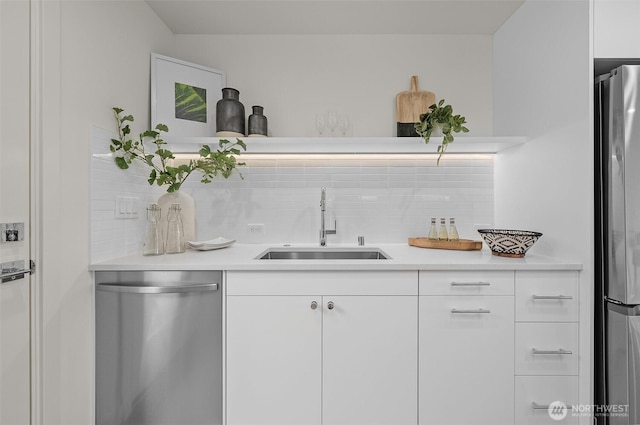 bar featuring tasteful backsplash, stainless steel appliances, sink, and white cabinets