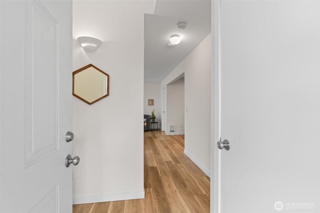 hall featuring light wood-style flooring and baseboards