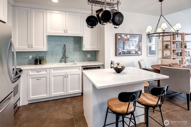 kitchen with appliances with stainless steel finishes, a sink, white cabinets, and decorative backsplash