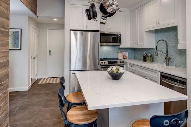 kitchen featuring stainless steel appliances, backsplash, a sink, dark tile patterned floors, and a kitchen breakfast bar