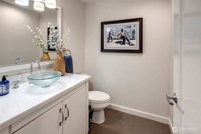 half bath featuring toilet, baseboards, and vanity