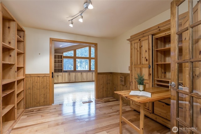 dining area with visible vents, rail lighting, light wood-style flooring, wainscoting, and wood walls