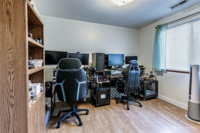 home office featuring light wood finished floors, baseboards, and visible vents