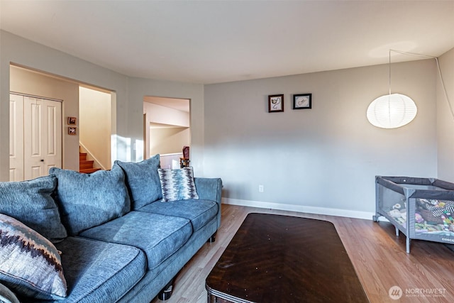 living room featuring stairway, baseboards, and wood finished floors