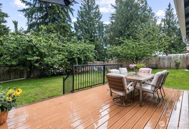 wooden terrace with outdoor dining space, a fenced backyard, and a yard