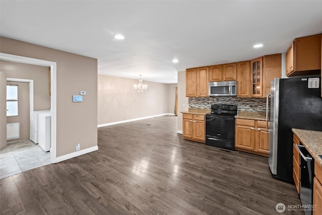 kitchen featuring hanging light fixtures, backsplash, black appliances, washing machine and clothes dryer, and dark hardwood / wood-style flooring