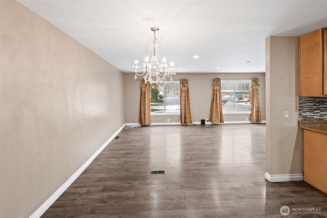 unfurnished dining area with an inviting chandelier and dark wood-type flooring