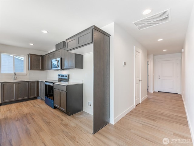 kitchen with dark brown cabinets, appliances with stainless steel finishes, sink, and light hardwood / wood-style flooring