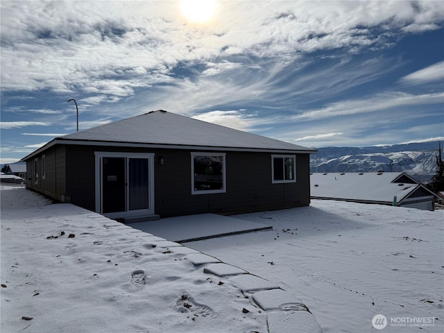 snow covered rear of property with a mountain view