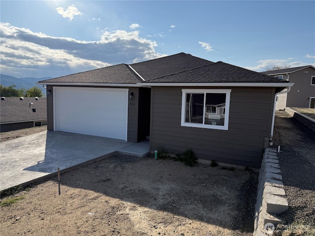 ranch-style home featuring a garage, driveway, a shingled roof, and a mountain view