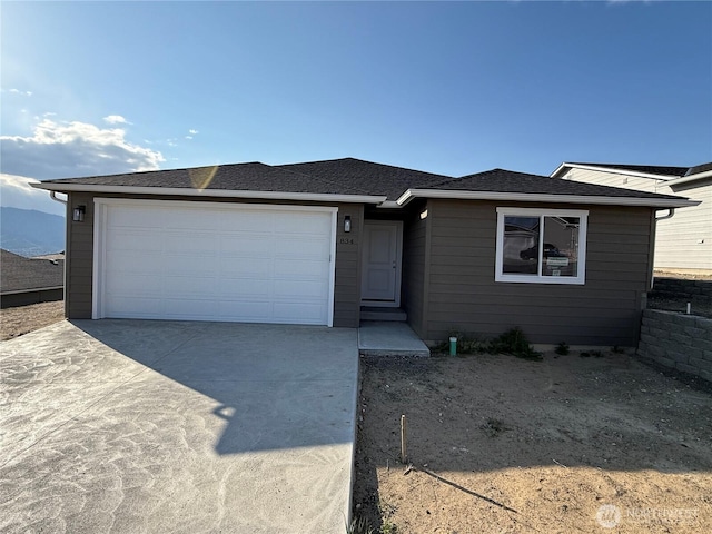 ranch-style home with driveway, a shingled roof, and a garage