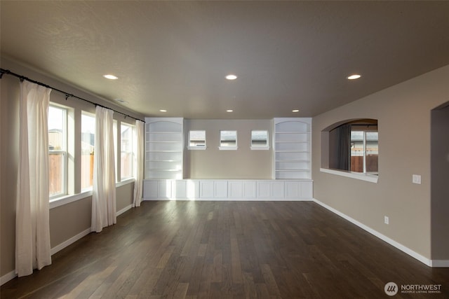 spare room featuring built in shelves and dark hardwood / wood-style floors