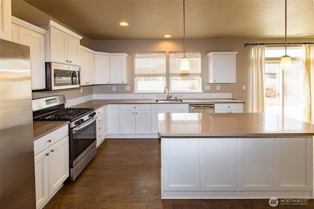 kitchen with white cabinetry, appliances with stainless steel finishes, sink, and hanging light fixtures