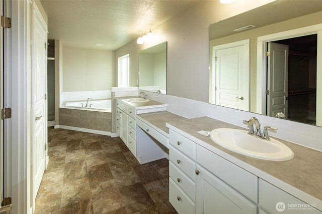 bathroom with tiled tub and vanity