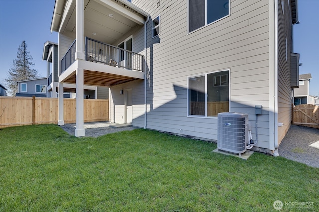 back of house featuring central AC unit, a yard, and a balcony