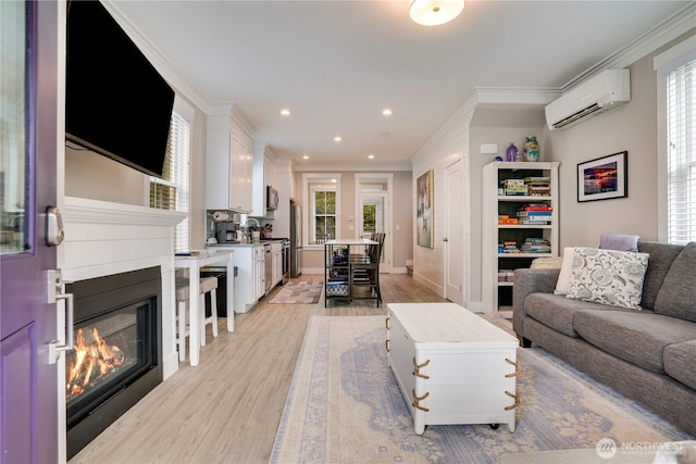 living room featuring a wall mounted AC, ornamental molding, light hardwood / wood-style floors, and a wealth of natural light