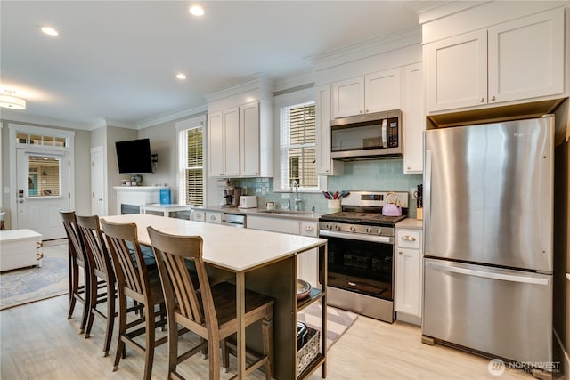 kitchen featuring white cabinetry, stainless steel appliances, sink, backsplash, and crown molding