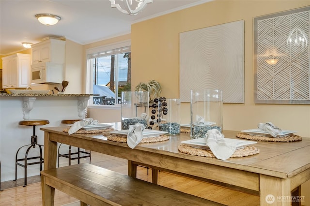 dining area featuring crown molding, light wood-style flooring, and an inviting chandelier