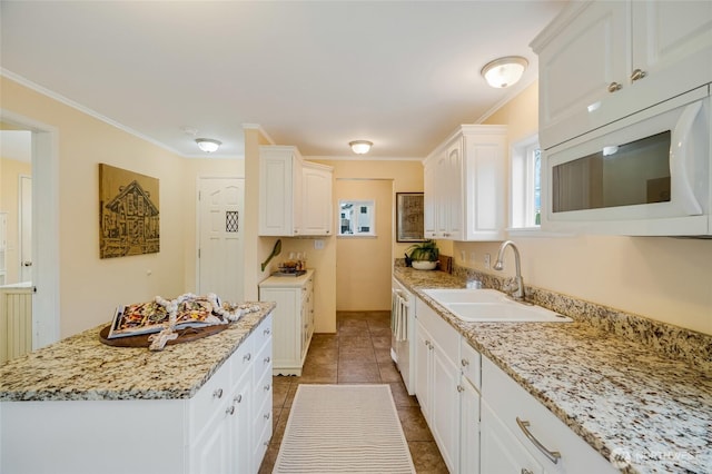 kitchen featuring white microwave, white cabinetry, a sink, and crown molding