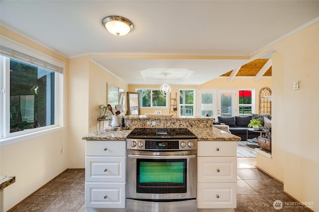 kitchen with light stone counters, a wealth of natural light, white cabinetry, and electric stove