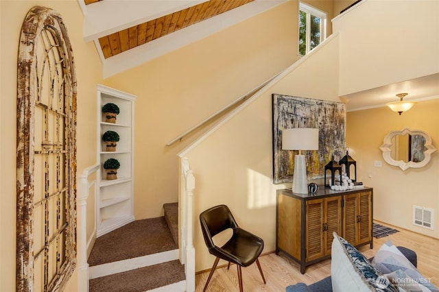 stairway featuring beamed ceiling, high vaulted ceiling, visible vents, wooden ceiling, and wood finished floors