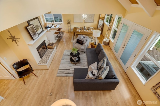 living room with a glass covered fireplace, wood finished floors, and a towering ceiling