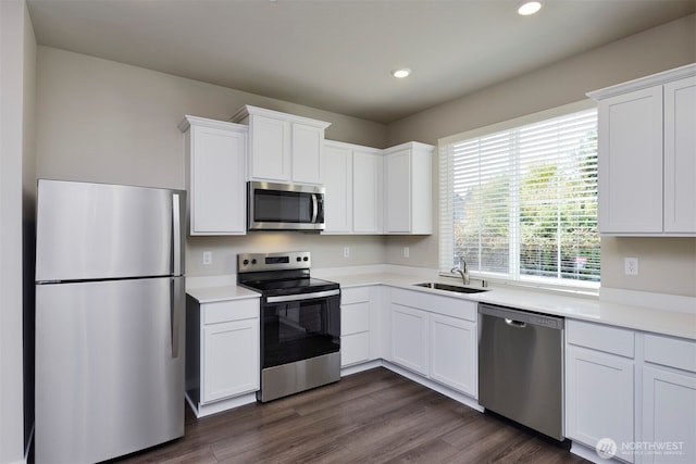 kitchen with stainless steel appliances, sink, white cabinets, and dark hardwood / wood-style floors