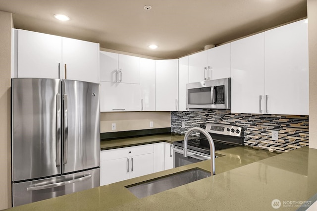 kitchen with a sink, stainless steel appliances, backsplash, and white cabinetry