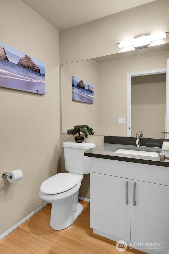 bathroom featuring baseboards, vanity, toilet, and wood finished floors