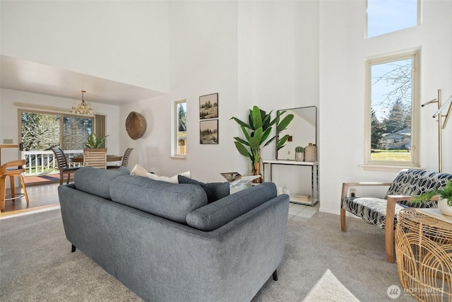 carpeted living room featuring an inviting chandelier and a high ceiling