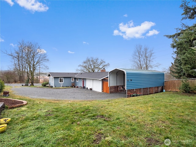 back of property featuring a lawn, fence, driveway, a carport, and a chimney