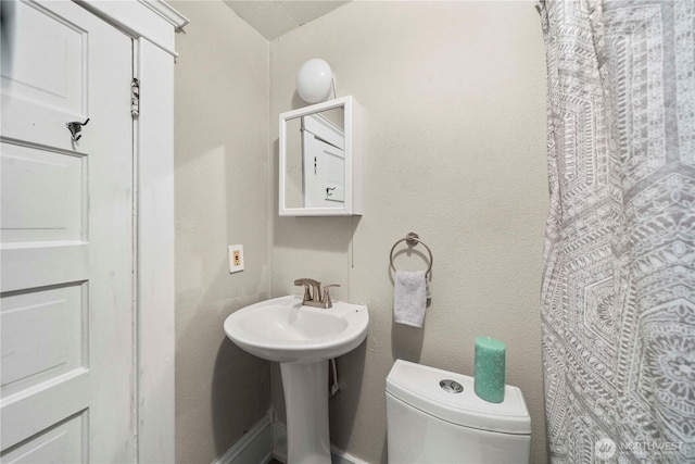 full bath featuring toilet and a textured wall