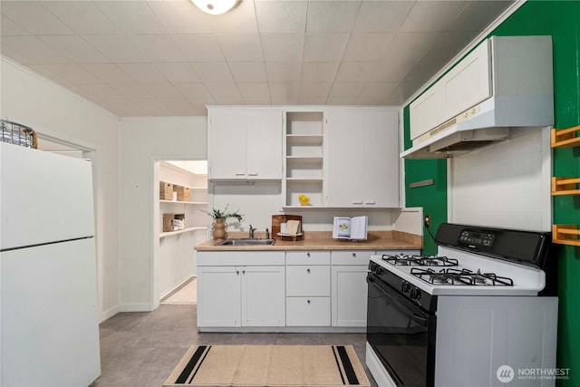 kitchen featuring open shelves, gas range, freestanding refrigerator, white cabinets, and a sink