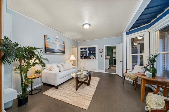 living room with dark wood-type flooring, built in shelves, and baseboards