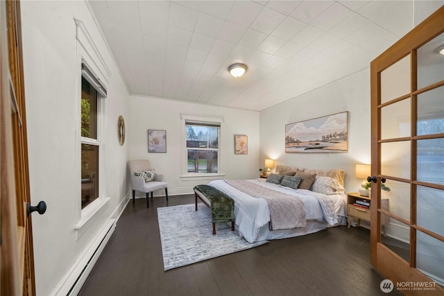 bedroom with a baseboard radiator, wood-type flooring, and baseboards