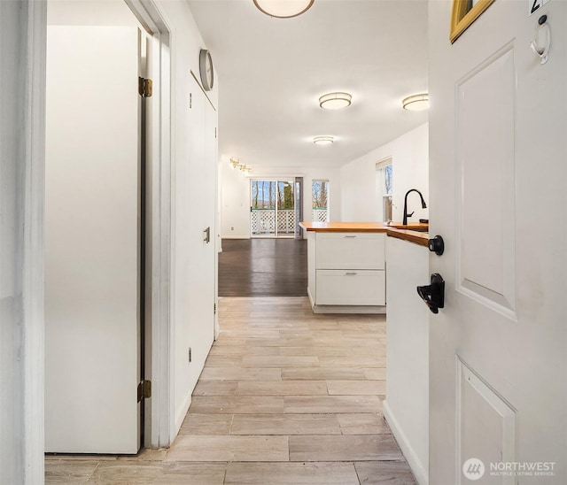 corridor with sink and light wood-type flooring