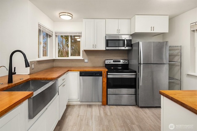 kitchen featuring wood counters, sink, stainless steel appliances, decorative backsplash, and white cabinets