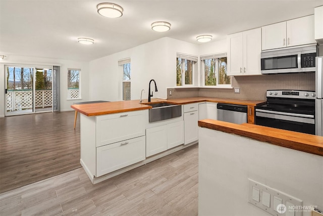 kitchen featuring tasteful backsplash, butcher block counters, sink, white cabinets, and stainless steel appliances