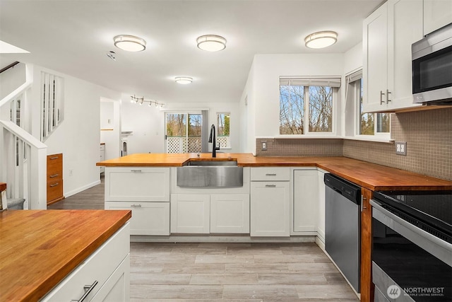 kitchen with white cabinetry, wooden counters, stainless steel appliances, and sink