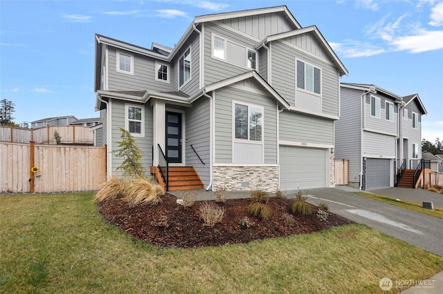 view of front facade with a garage, entry steps, stone siding, fence, and a front yard