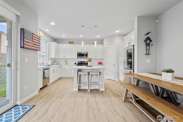 kitchen featuring light wood-style floors, a kitchen island, stainless steel appliances, and backsplash