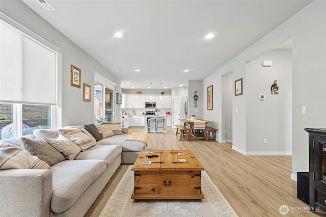 living area with light wood-style floors, visible vents, baseboards, and recessed lighting