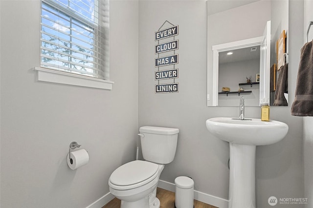 half bath with wood finished floors, toilet, and baseboards