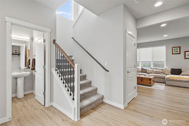 staircase featuring baseboards, wood finished floors, and recessed lighting