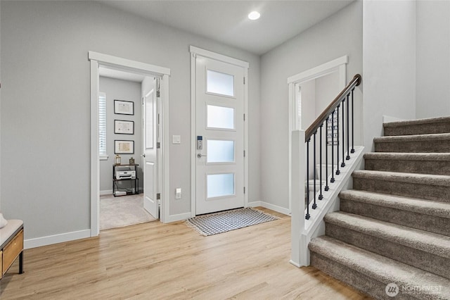 foyer featuring light wood finished floors, stairway, plenty of natural light, and baseboards